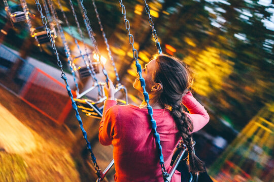 Young woman riding on a swing carousel in amusement park smiling