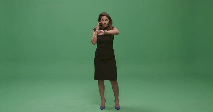 Studio, slow motion, green screen, an adult woman on the phone checks her watch, London, UK