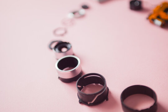 Separated parts of the camera lens on pink background.