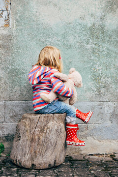 People: Portrait of a little with Teddy in front of a green wall, not wanting to be photographed