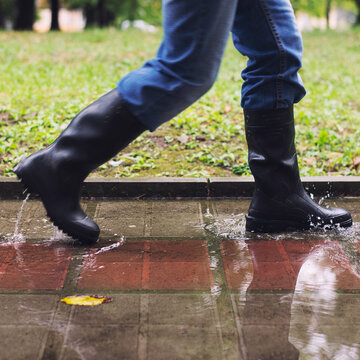Feet in boots stepping in puddle