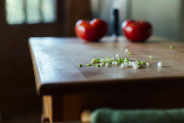 Chopped spring onions with two tomatoes sit in sunlight..