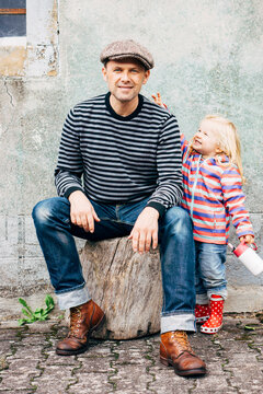 People: Little girl makes fun (reaching out for the hat) while her father is sitting for a Portrait