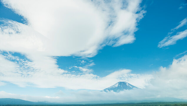 Mount Fuji rising up through a sea of clouds under blue sky in Japan.