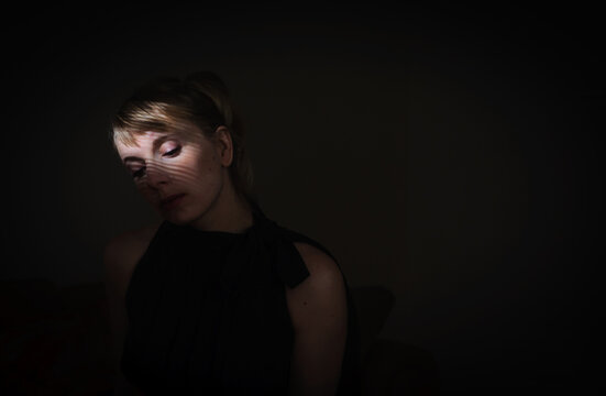woman sitting in a dark room with her face partially lit