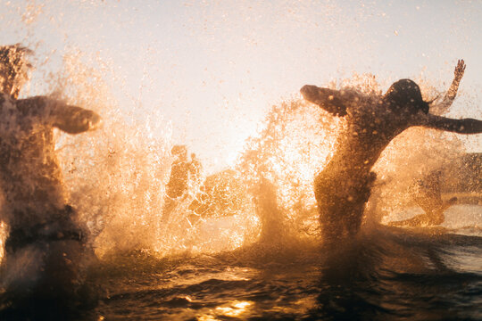 A rowdy group of young friends runs into oncoming ocean waves