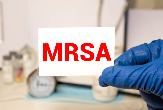 Doctor's hands in blue gloves shows the word MRSA Medical concept.