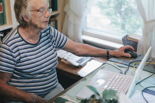 Senior Woman Using Computer and Internet Technology at Home in her Study