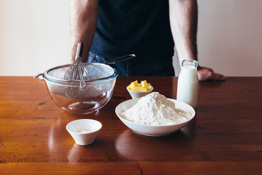 Man standing at a table with basic dishes and ingredients required for baking