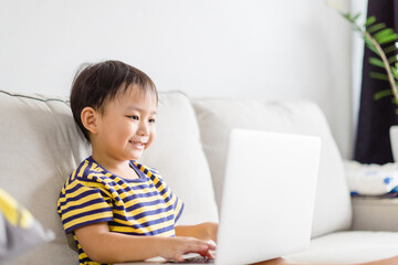 Asian toddler boy student study online learning online education video call zoom teacher.Happy boy learn english online with laptop at home.New normal.Covid-19 coronavirus.Social distancing.stay home.