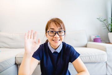 Asian woman teacher smiling at camera at home during coronavirus covid19 crisis.Lockdown and Teach...