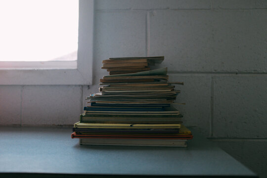Pile of old books, and magazines beside a window