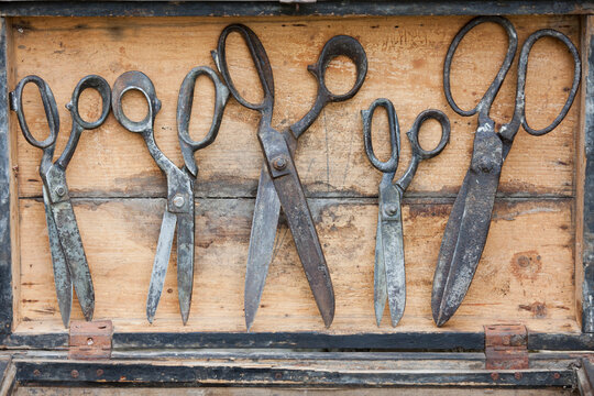 Old assorted scissors in a row on textured wood background