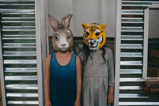 Two girls stand in door frame wearing animal masks