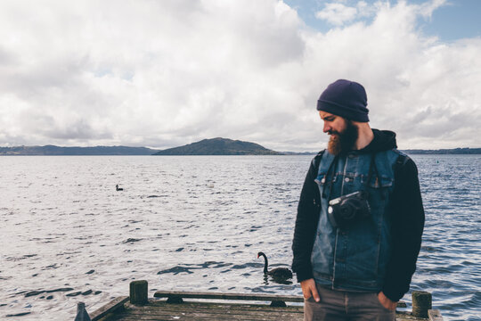 Man with a beard with polaroid on background of lake