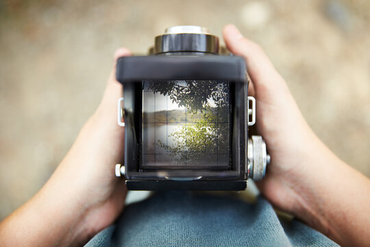 Hands taking picture of a lake with TLR camera