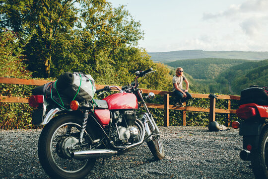 Motorcyclist taking a break on the side of the road.