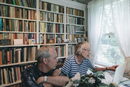 Adult Son Showing Senior Mother How to Use Computer Technology in Study at Home