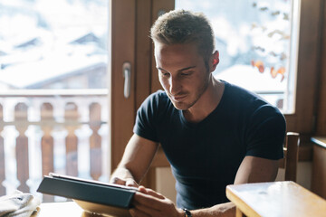 Young man is using the tablet in the kitchen