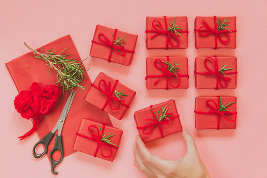 Hand placing red christmas gift in a gift wrapping setup