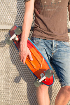 Teenager with skateboard near a grid wall