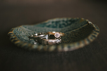Closeup of wedding rings in a handmade pottery dish