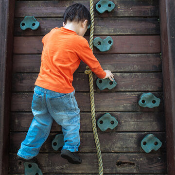 Young boy climbing up a wall.