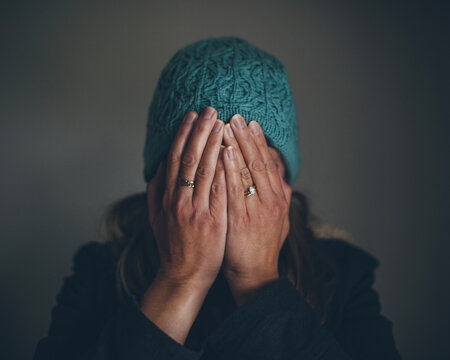 woman in a dark space covers her face with her hands