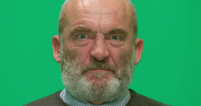 Studio, slow motion, a portrait of a seething mature man against a green screen, London, UK