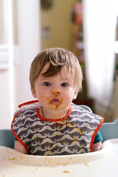 Young baby boy makes a mess while he eats.