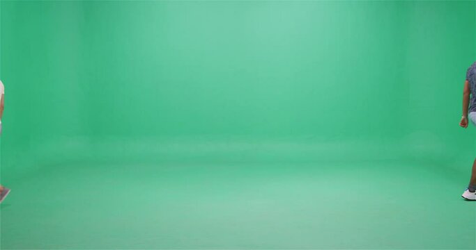 Two men passing each other, giving high five, greenscreen