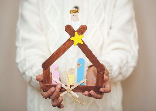 child holding Christmas nativity craft