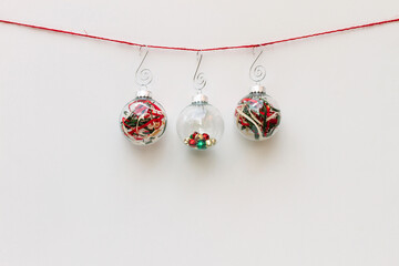 Three glass Christmas ornaments hanging on red string
