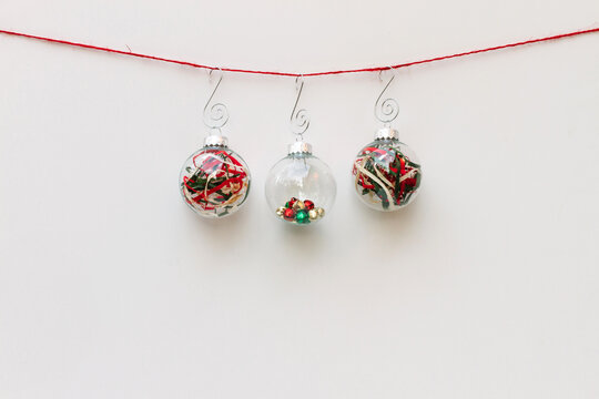 Three glass Christmas ornaments hanging on red string