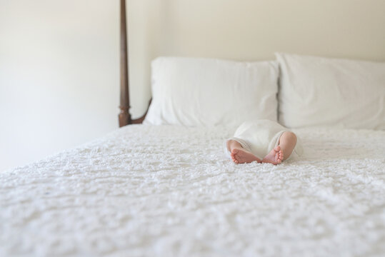 A Newborn Baby Lies On A White Bed