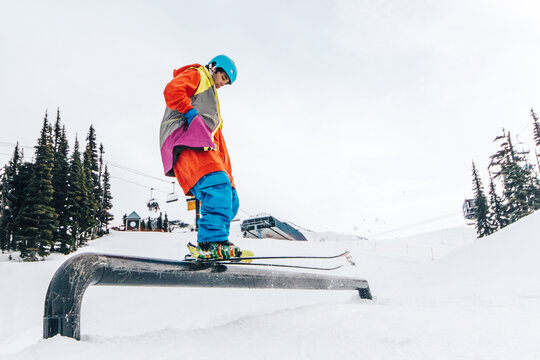 Skier sliding on a rail in a snowpark of ski resort with hands in the pockets looking cool