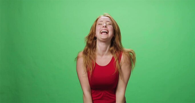 Redhead young woman laughing and jumping, greenscreen, slow motion