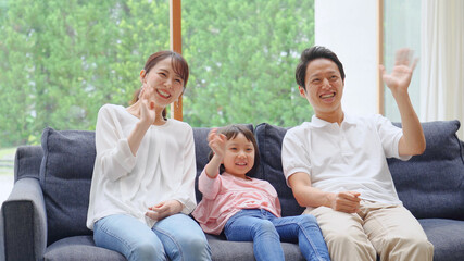 ソファーで手を振る親子
