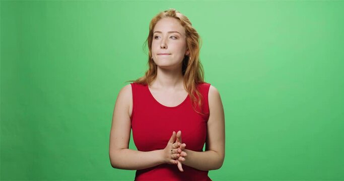Redhead woman biting lips and rubbing hands, greenscreen, slow motion