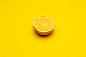 Rodaja de naranja sobre fondo amarillo. Concepto minimalista de verano.