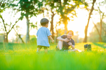 Happy child and his mom have fun outdoors on green grass field