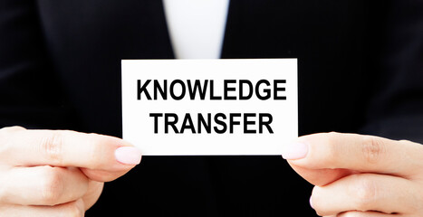 The business card with knowledge TRANSFER is held by a businessman in front of him.