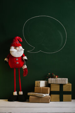 Santa Claus standing in front of the green chalkboard with drawn speech bubble