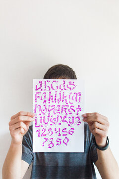 Young man holding artwork calligraphy design in front of his face