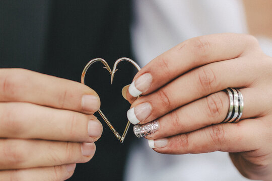 bride and groom holding two fishing hooks together forming a heart