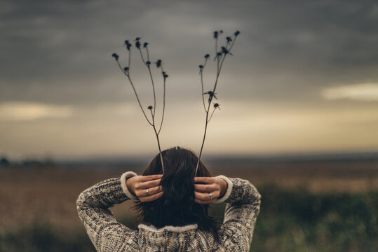 Young woman holing branches above her head.