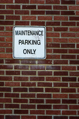 Fototapeta na wymiar White parking sign on a red brick wall 