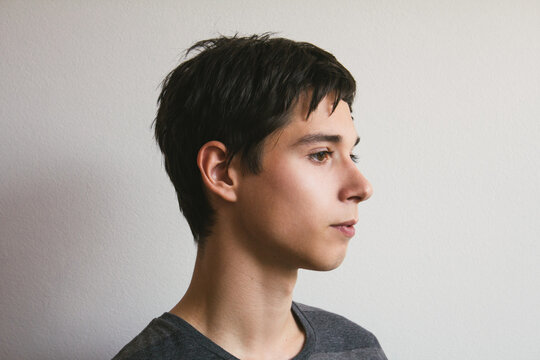 Simple natural light profile headshot image of a teenage boy in front of white wall