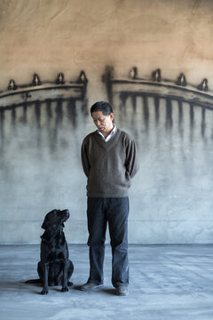 A man and dog in front of a wall with a gate painting on it
