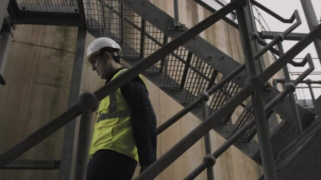 Industrial worker walking up stairs on industrial site wearing protective workwear